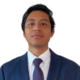 Photo of René Cano: portrait in a navy blazer, white shirt and tie.